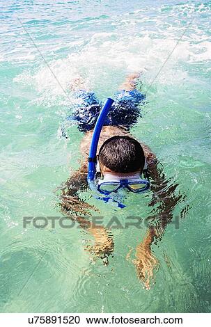 Stock Image - Boy (10-11) snorkeling in sea. Fotosearch