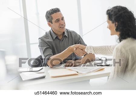 Stock Image - Business people talking at desk in office. Fotosearch