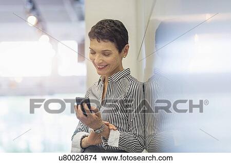 Picture - Businesswoman using smartphone. Fotosearch