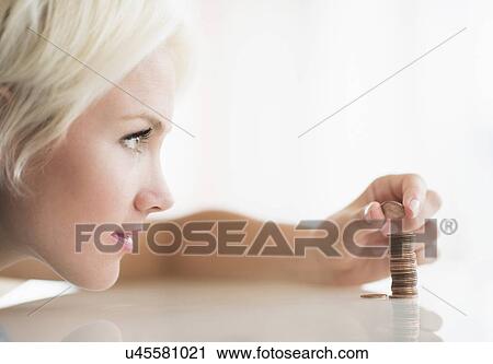 Stock Image - Close-up of woman stacking coins. Fotosearch