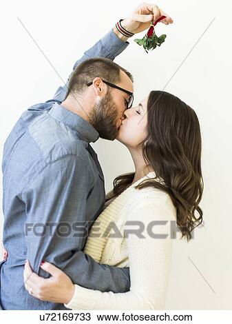 Stock Image - Couple kissing under mistletoe. Fotosearch