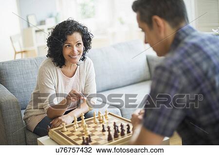 Stock Image - Couple playing chess in living room. Fotosearch