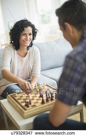 Stock Photo - Couple playing chess in living room. Fotosearch