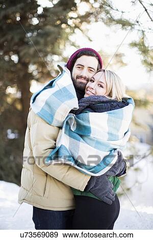 Couple wrapped in blanket hugging outdoors View Large Photo Image Stock Photo - Couple wrapped in blanket hugging outdoors. Fotosearch