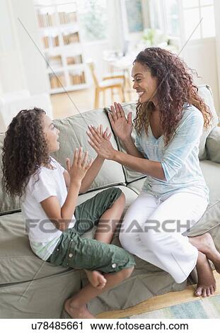 Stock Image - Daughter (8-9) and mother playing clapping game . Fotosearch