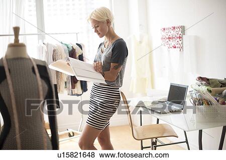Stock Photo - Designer looking at sketchbook in studio. Fotosearch