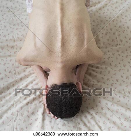 Stock Photo - Elevated view of shirtless woman bending on bed. Fotosearch