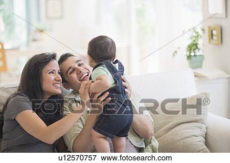 Family with baby son (6-11 months) in living room View Large Photo Image Stock Photo - Family with baby son (6-11 months) in living room. Fotosearch