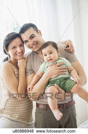 Stock Photo - Family with baby son (6-11 months) in bedroom. Fotosearch