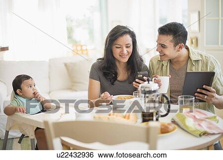 Family with baby son (6-11 months) in dining room View Large Photo Image Stock Photograph - Family with baby son (6-11 months) in dining room. Fotosearch