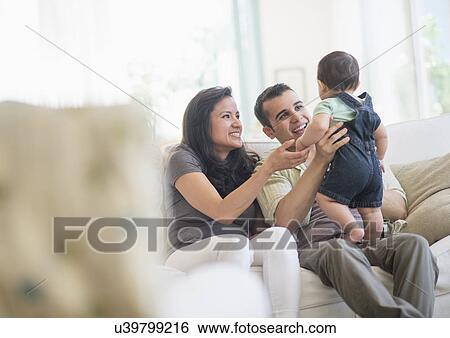 Stock Photograph - Family with baby son (6-11 months) in living room. Fotosearch