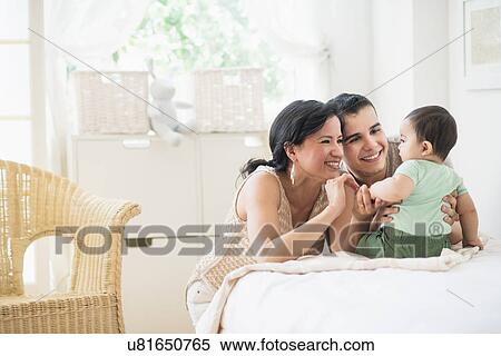 Stock Photography - Family with baby son (6-11 months) in bedroom. Fotosearch