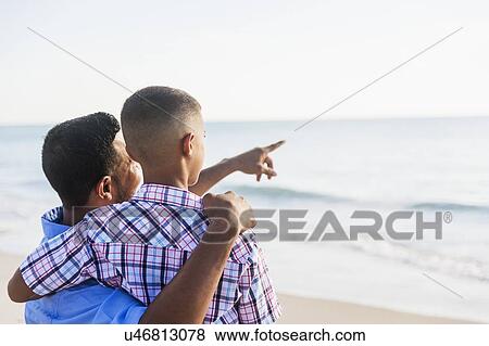 Father and son (10-11) embracing on beach View Large Photo Image Stock Photo - Father and son (10-11) embracing on beach. Fotosearch