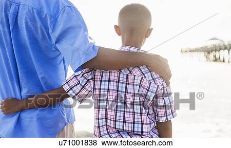 Father and son (10-11) embracing on beach View Large Photo Image Stock Photo - Father and son (10-11) embracing on beach. Fotosearch