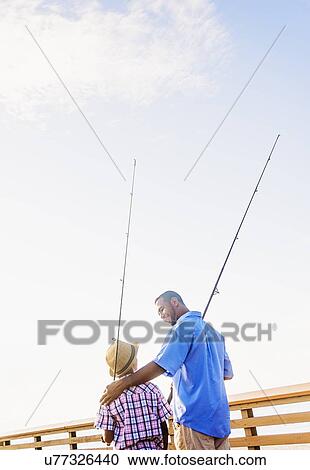 Stock Image - Father and son (10-11) fishing. Fotosearch