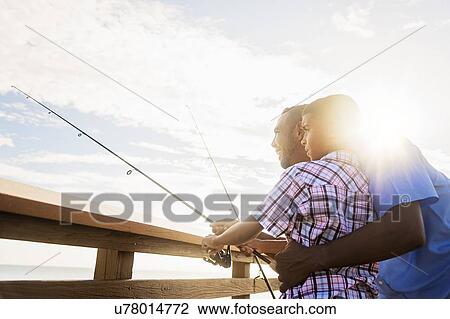 Stock Image - Father and son (10-11) fishing. Fotosearch