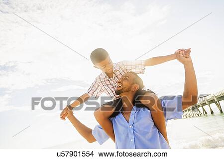 Father and son (10-11) having fun on beach View Large Photo Image Picture - Father and son (10-11) having fun on beach. Fotosearch