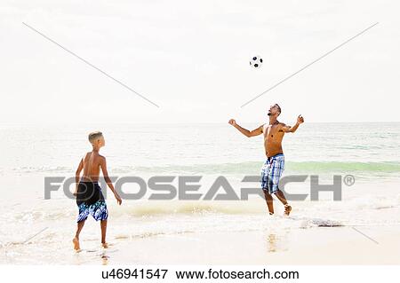 Father and son (10-11) playing soccer on beach View Large Photo Image Stock Photo - Father and son (10-11) playing soccer on beach. Fotosearch