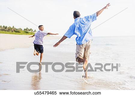 Father and son (10-11) running on beach View Large Photo Image Stock Photography - Father and son (10-11) running on beach. Fotosearch