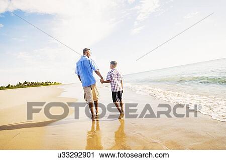 Father and son (10-11) walking on beach View Large Photo Image Stock Image - Father and son (10-11) walking on beach. Fotosearch