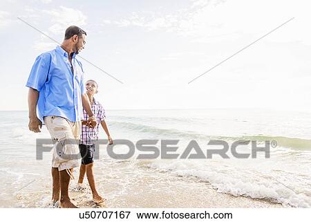 Father and son (10-11) walking on beach View Large Photo Image Stock Photo - Father and son (10-11) walking on beach. Fotosearch