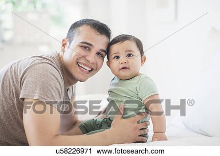 Stock Image - Father holding his son (6-11 months). Fotosearch