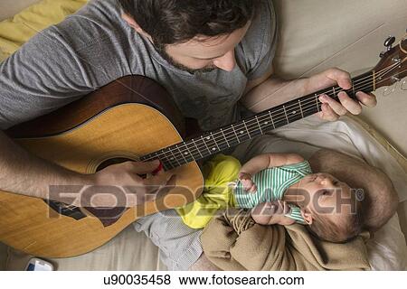 Father playing guitar for newborn daughter View Large Photo Image Stock Photo - Father playing guitar for newborn daughter. Fotosearch