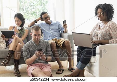 Friends hanging out in living room View Large Photo Image Picture - Friends hanging out in living room. Fotosearch