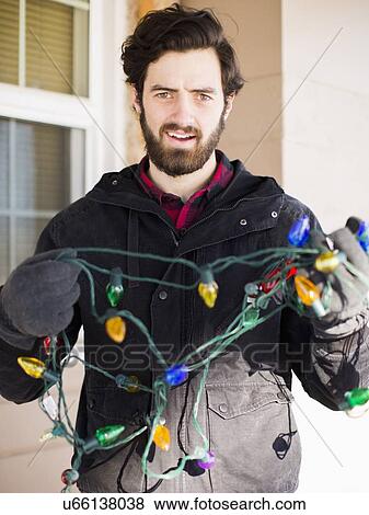 Front view portrait of young man with Christmas light View Large Photo Image Stock Photo - Front view portrait of young man with Christmas light. Fotosearch