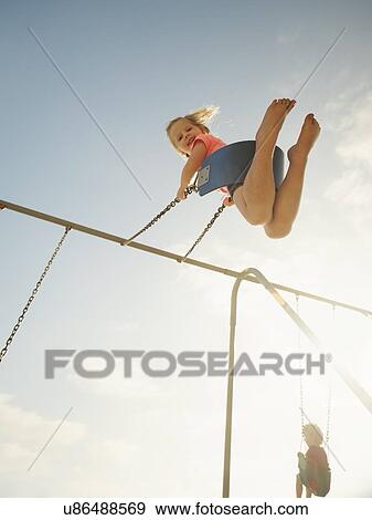 Girl (4-5) and boy (2-3) swinging on beach View Large Photo Image Stock Photo - Girl (4-5) and boy (2-3) swinging on beach. Fotosearch