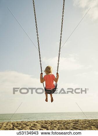Girl (4-5) swinging on beach View Large Photo Image Stock Image - Girl (4-5) swinging on beach. Fotosearch