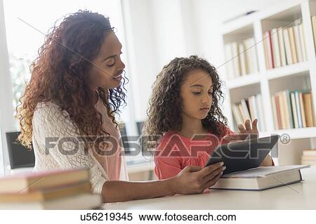 Stock Photography - Girl (8-9) and teacher using digital tablet in classroom. Fotosearch