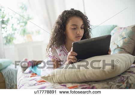 Girl (8-9) using digital tablet on bed View Large Photo Image Stock Image - Girl (8-9) using digital tablet on bed. Fotosearch