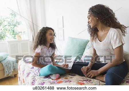 Stock Photo - Girl (8-9) using digital tablet on bed. Fotosearch
