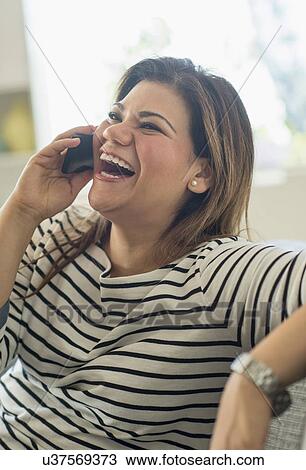 Happy woman sitting on sofa with mobile phone View Large Photo Image Stock Image - Happy woman sitting on sofa with mobile phone. Fotosearch