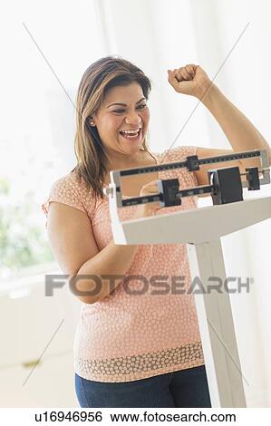 Stock Photograph - Happy woman standing on scale. Fotosearch