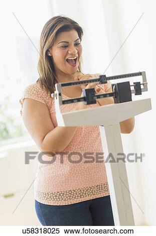 Stock Photography - Happy woman standing on scale. Fotosearch