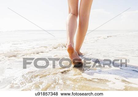 Stock Photo - Legs of woman walking in sea. Fotosearch