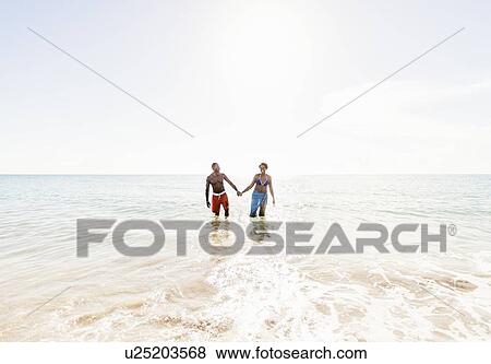 Stock Photo - Man and woman holding hands on beach. Fotosearch