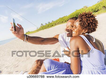Man and woman photographing self on beach View Large Photo Image Stock Photo - Man and woman photographing self on beach. Fotosearch
