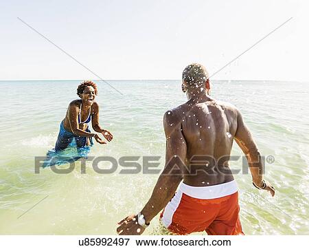 Man and woman splashing water on beach View Large Photo Image Stock Photo - Man and woman splashing water on beach. Fotosearch
