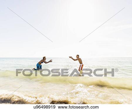 Man and woman splashing water on beach View Large Photo Image Stock Photo - Man and woman splashing water on beach. Fotosearch