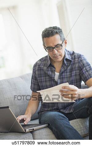 Stock Photo - Man doing home finances with laptop. Fotosearch