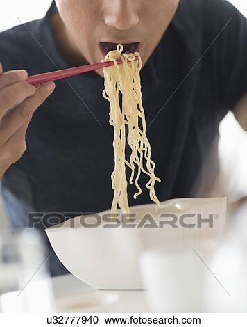 Man eating noodles with chopsticks View Large Photo Image Stock Image - Man eating noodles with chopsticks. Fotosearch