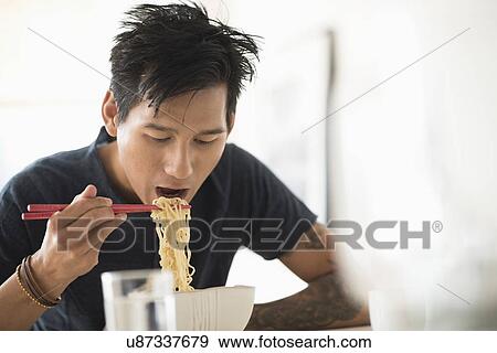 Man eating noodles with chopsticks View Large Photo Image Stock Photo - Man eating noodles with chopsticks. Fotosearch