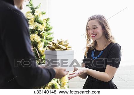 Man giving present to woman at Christmas View Large Photo Image Stock Photo - Man giving present to woman at Christmas. Fotosearch
