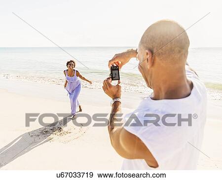Man photographing woman on beach View Large Photo Image Stock Photo - Man photographing woman on beach. Fotosearch