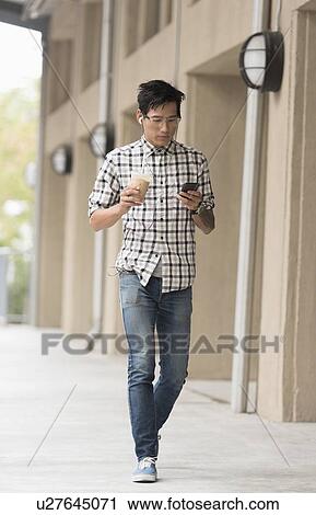 Man walking on sidewalk with iced coffee and mobile phone View Large Photo Image Stock Image - Man walking on sidewalk with iced coffee and mobile phone. Fotosearch