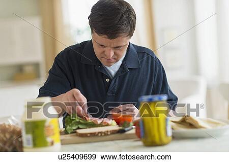 Man with down syndrome making sandwich View Large Photo Image Stock Photo - Man with down syndrome making sandwich. Fotosearch