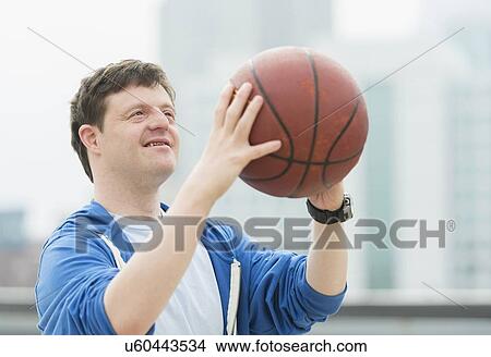 Picture - Man with down syndrome playing basketball. Fotosearch